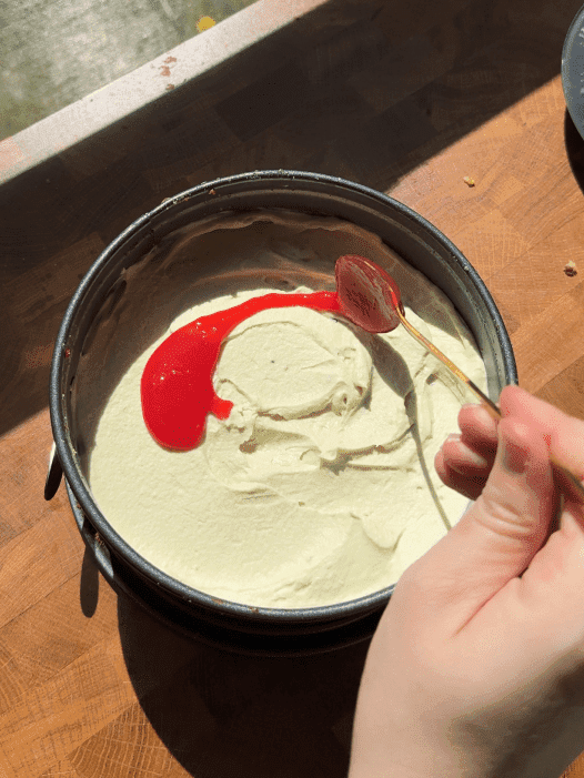 Spreading raspberry jam on top of the cake.