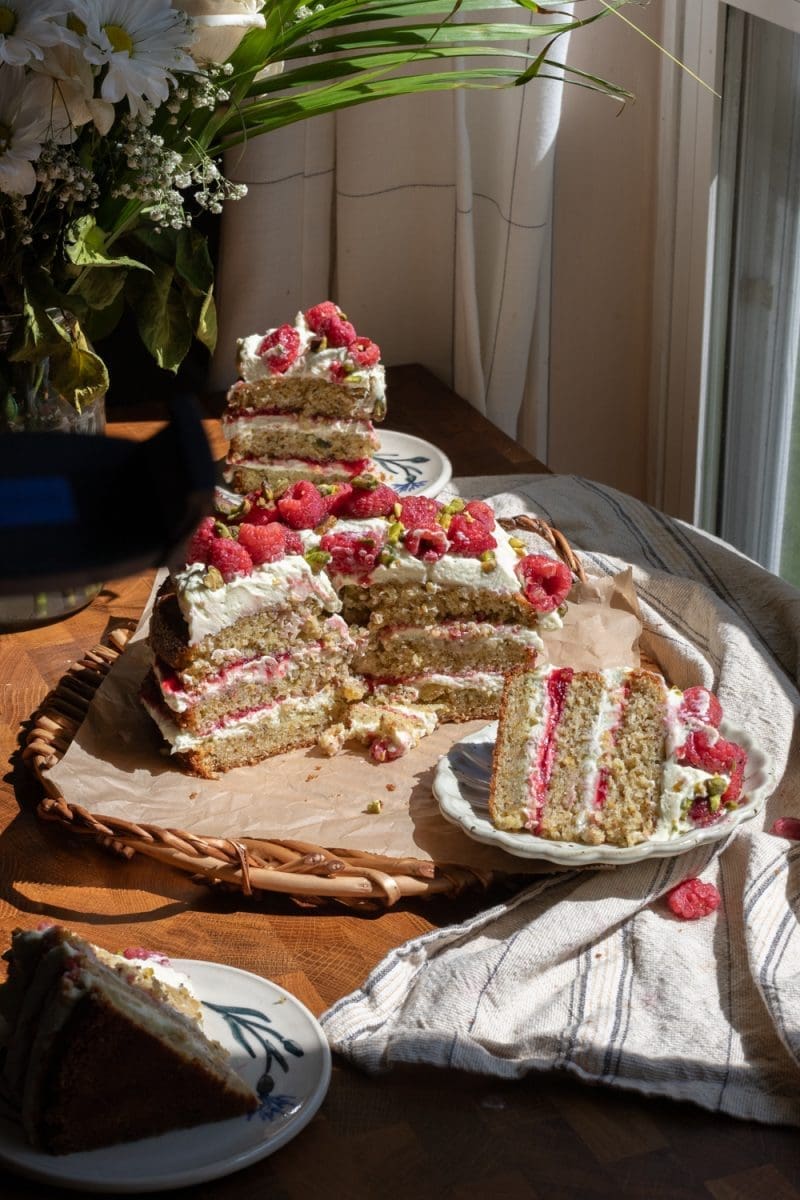 Pistachio raspberry cake sliced up on a serving tray.