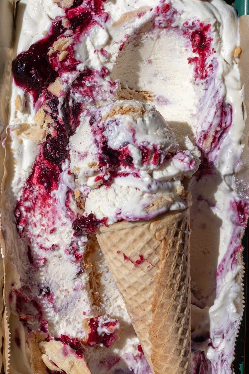 Close up of the no-churn blueberry pie ice cream in a cone on top of the pan full of ice cream.