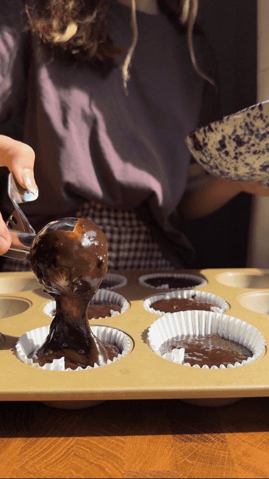 Pouring the cupcake batter into individual liners.