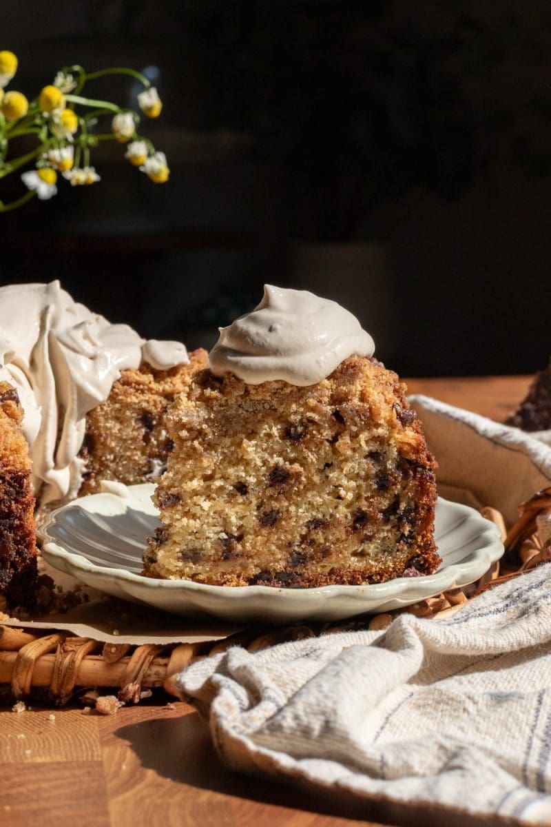 Close up slice of the banana chocolate chip crumb cake with a dollop of espresso whipped cream on top.