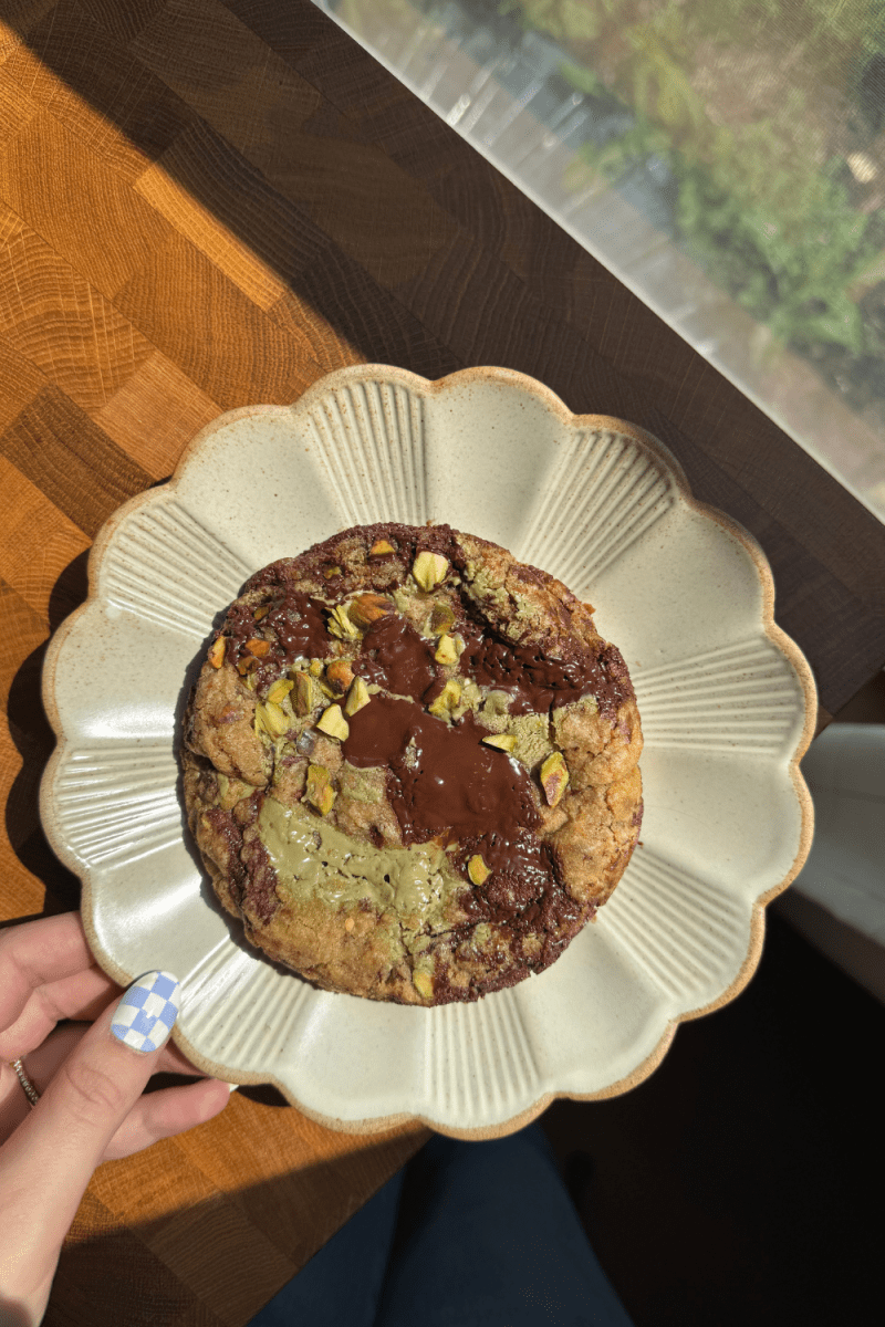 Holding a plate with the single serve pistachio cream chocolate chip cookie on it.