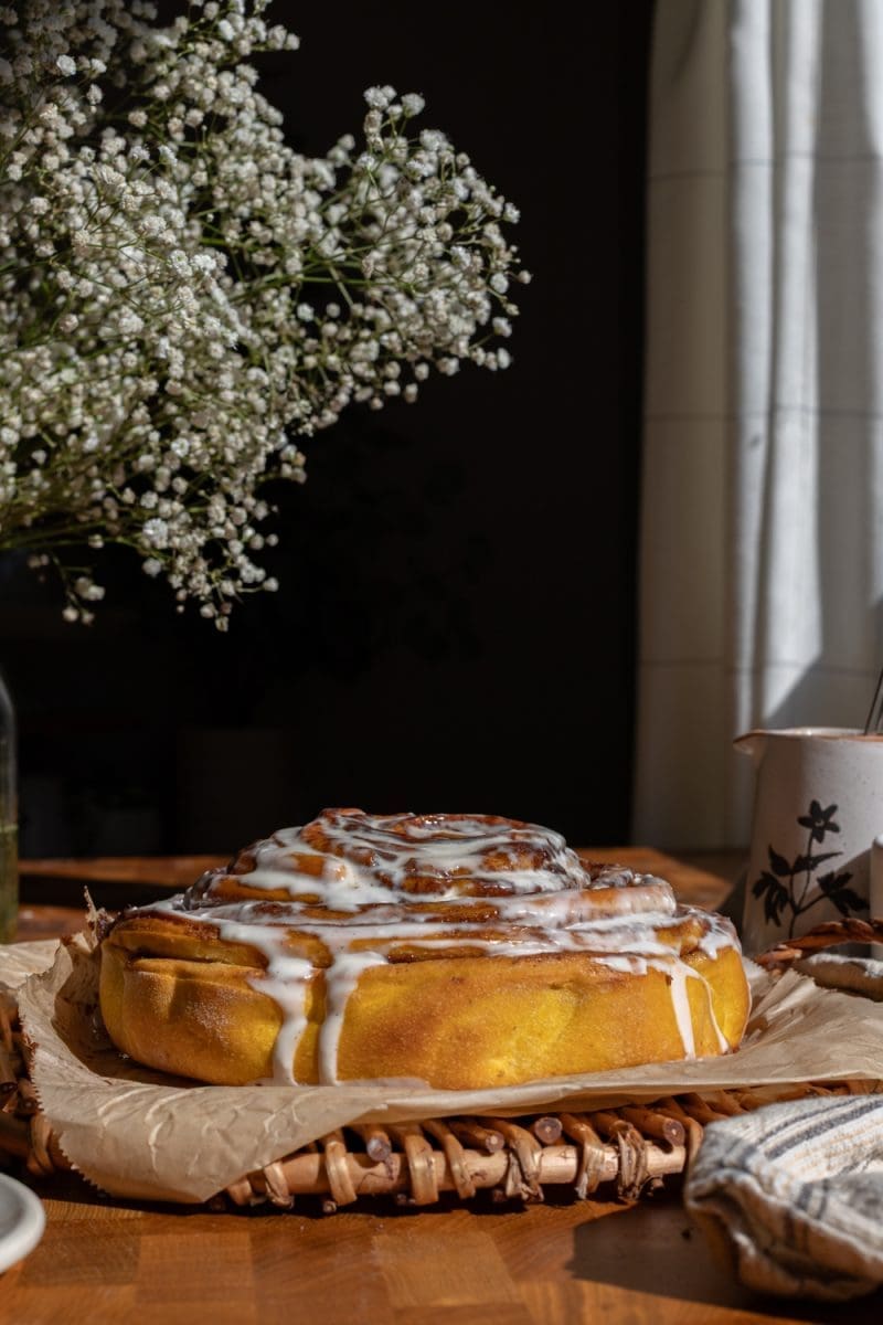 The giant pumpkin cinnamon roll sitting on a serving tray.