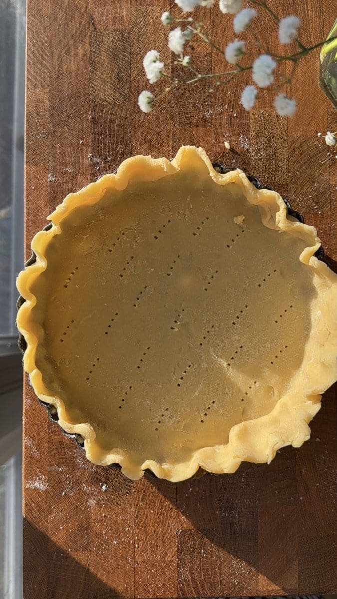 The pie crust crimped in a pan.