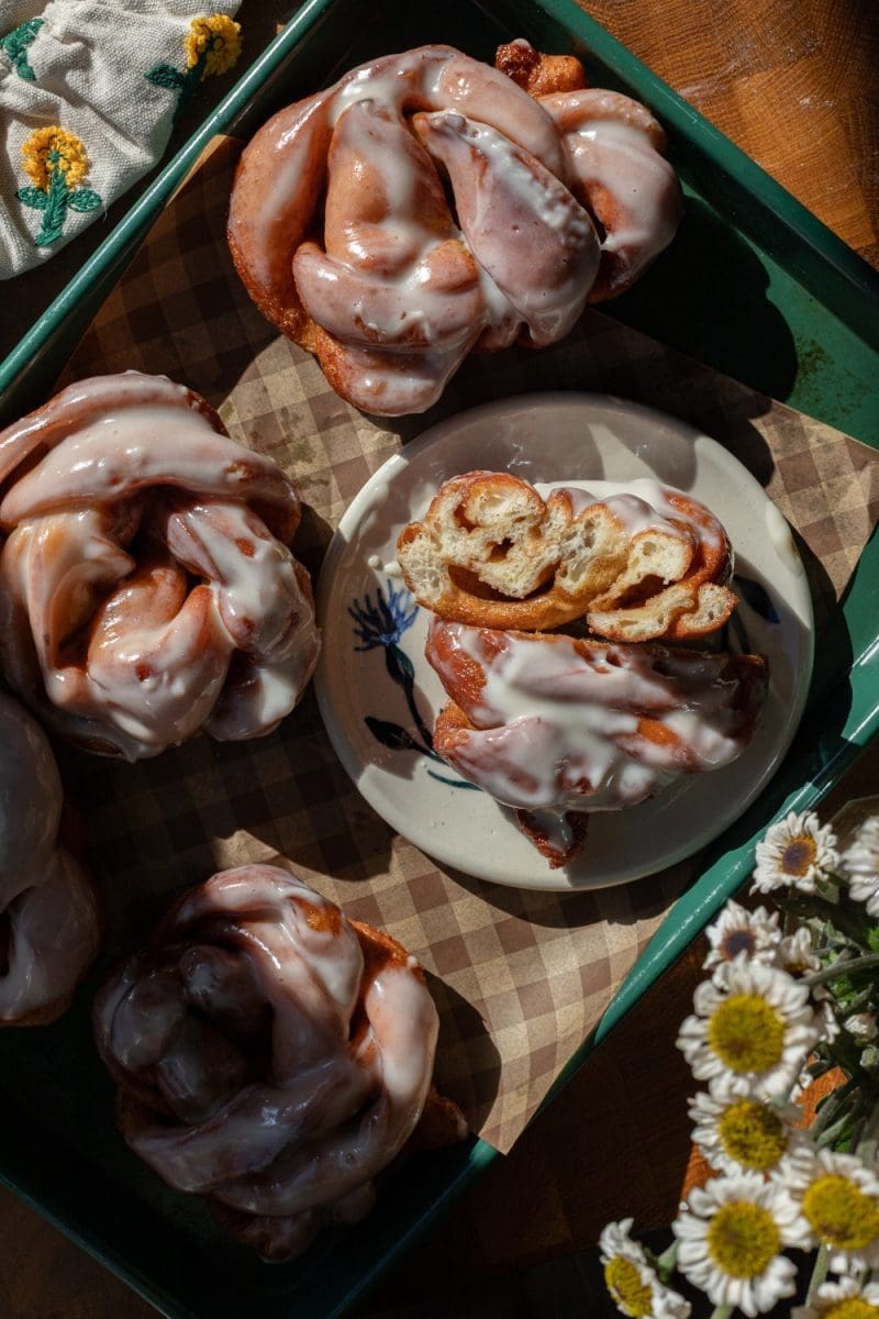 One of the cinnamon roll donuts cut in half on a plate.