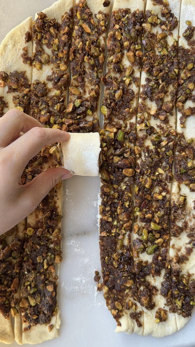Rolling up the pistachio cinnamon rolls.